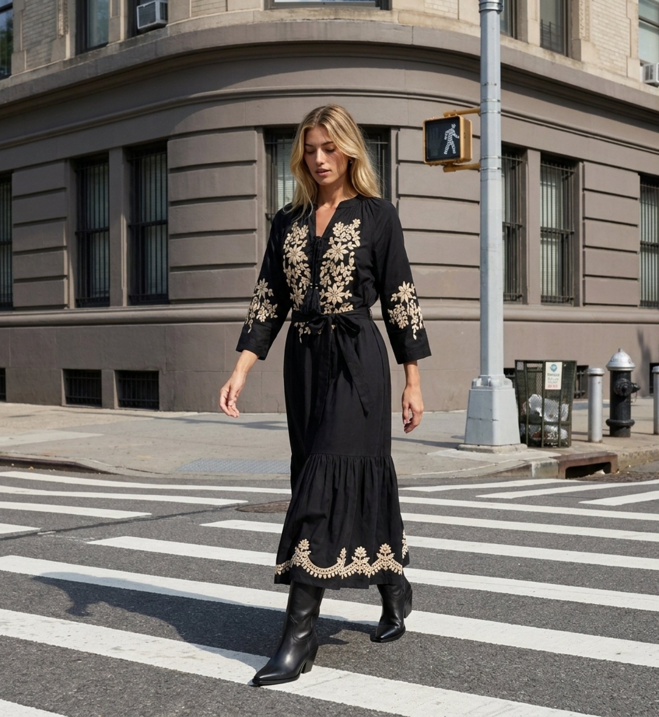 Black midi peasant dress with loose silhouette, gold floral embroidery on bodice, sleeves, hem, and tie-waist, worn by model.