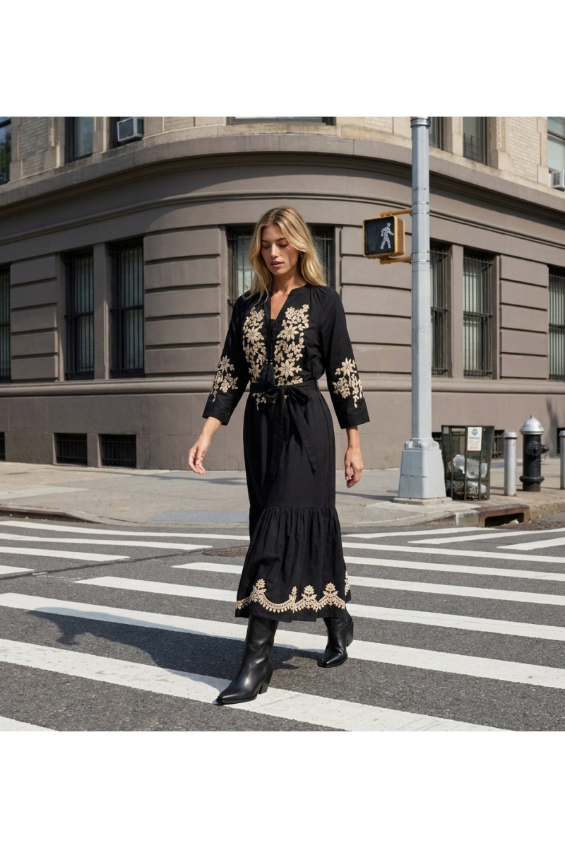 Black midi peasant dress with loose silhouette, gold floral embroidery on bodice, sleeves, hem, and tie-waist, worn by model.