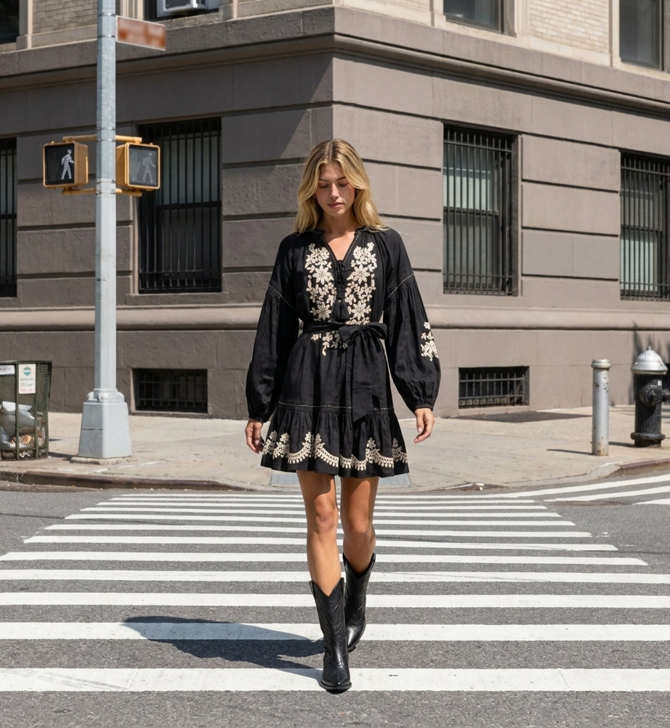 Black mini dress with white floral embroidery, loose fit, balloon sleeves, tiered skirt, tie-waist. Outdoor model shot.
