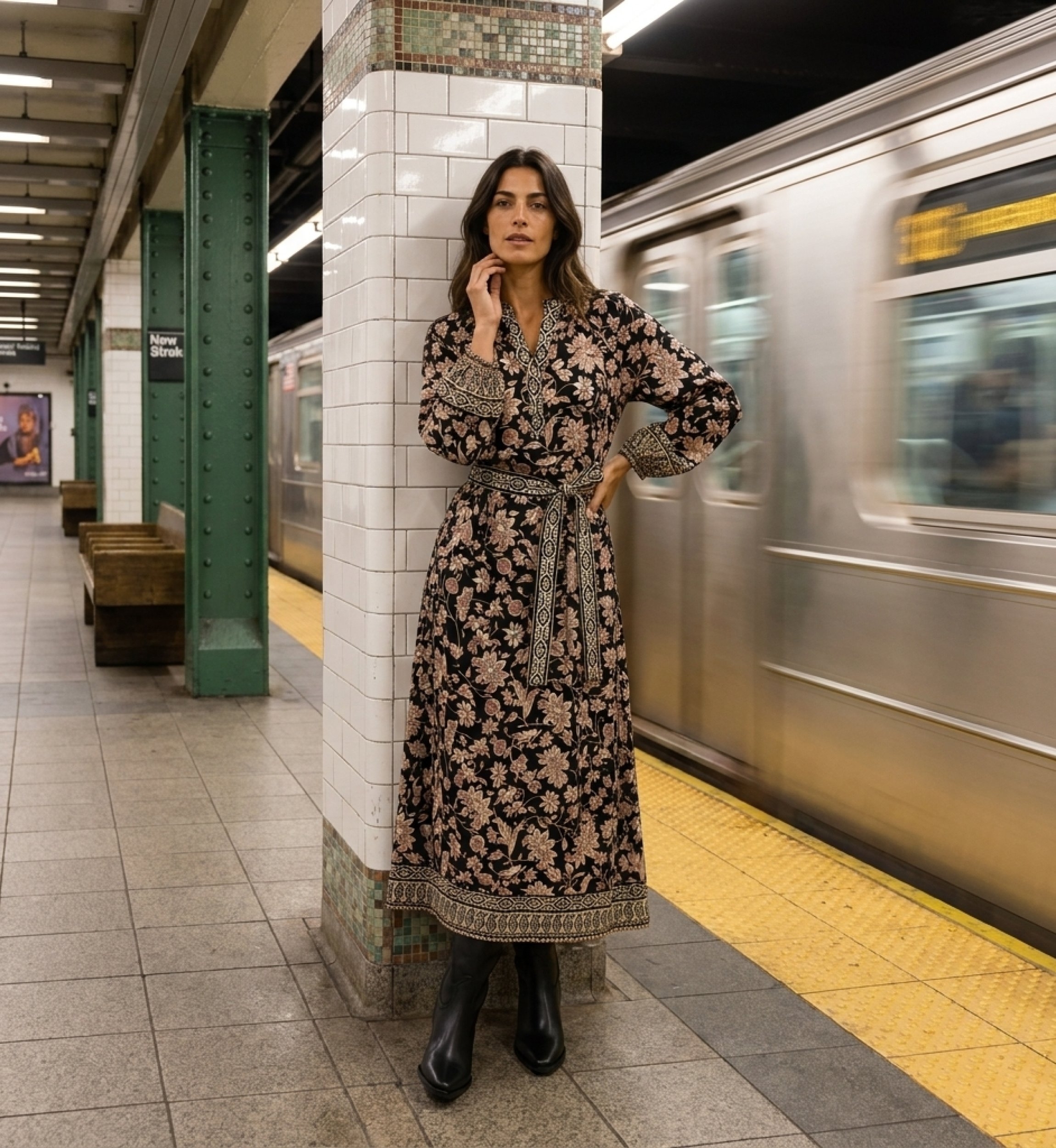 Black midi dress with beige/red floral pattern, V-neck, long balloon sleeves, tie-waist belt. Urban subway blur.