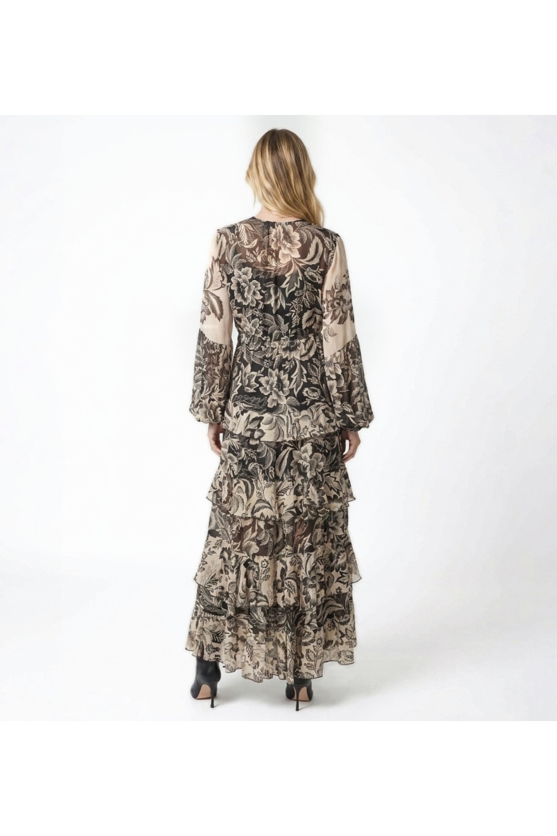 Back view of a black and beige floral print maxi dress with long sleeves, elasticated waist, and tiered ruffled skirt.