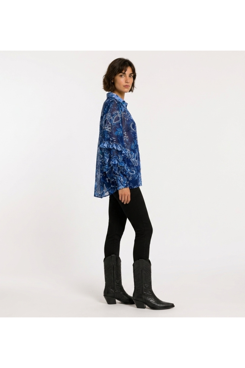 Three-quarter view of a blue sheer long-sleeve blouse with paisley floral print, ruffled cuffs, and a collared V-neck.