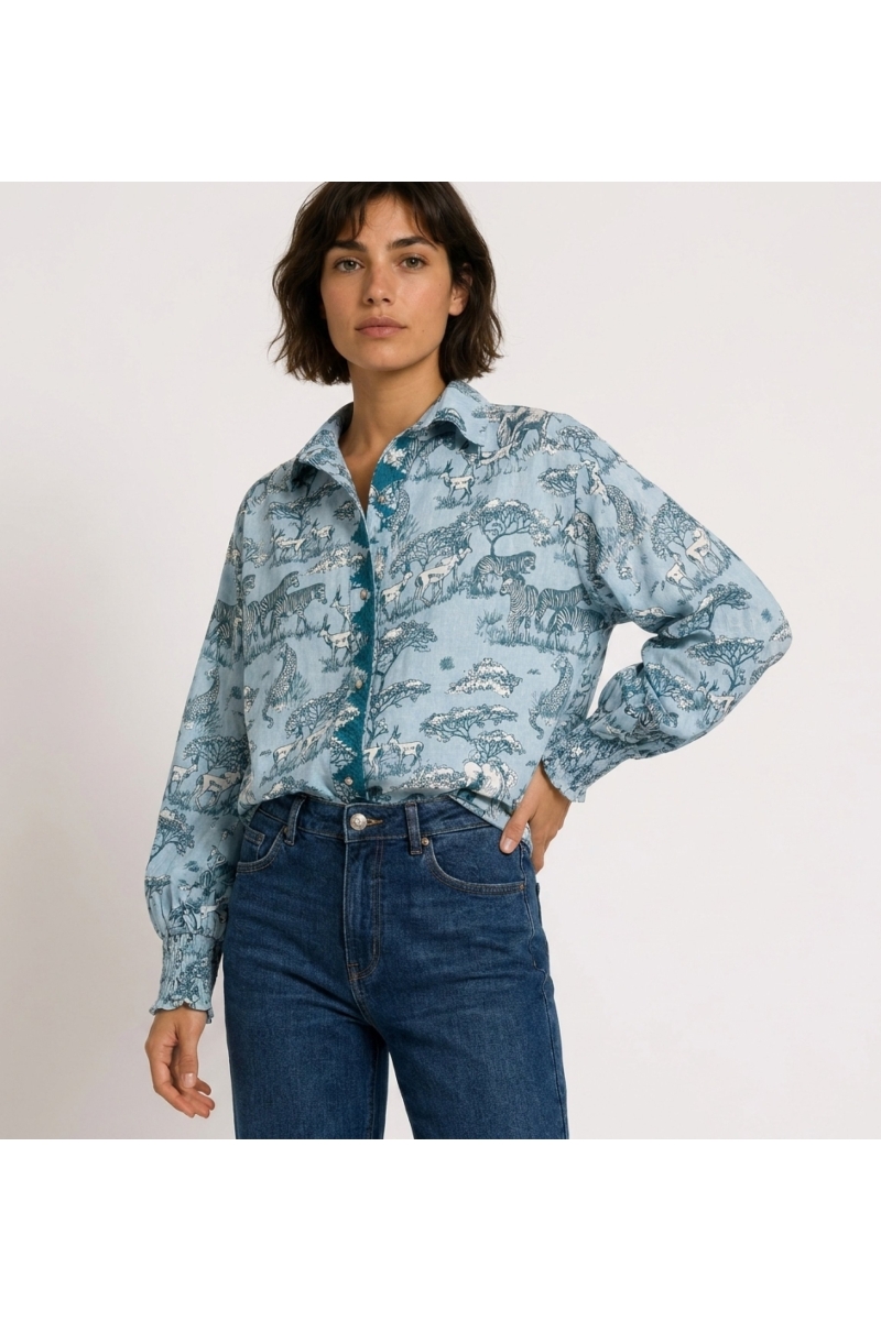 Light blue long-sleeve button-up shirt with dark blue and white safari animal pattern, puffed sleeves, shirred cuffs. Three-quar