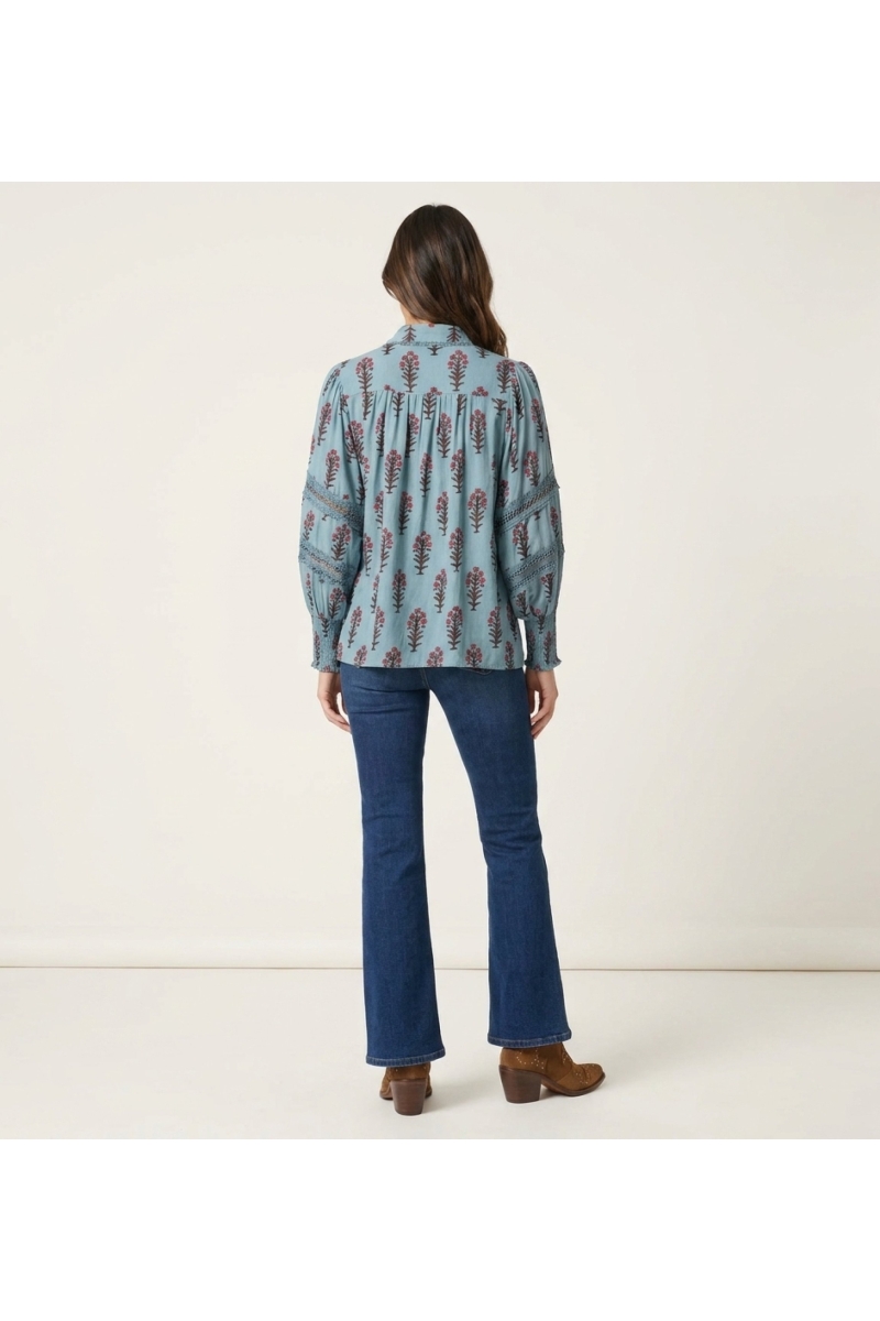 Blusa azul clara floral manga longa, costas. Padrão rosa e marrom, mangas balão com renda, punhos franzidos.