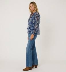 Three-quarter view of a sheer blue floral long-sleeve blouse with ruffled shoulders, cuffs, and drawstring neckline.