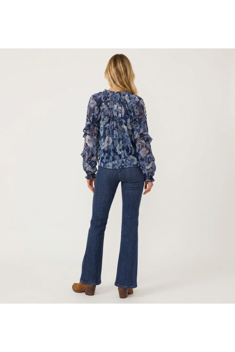 Back view of a sheer blue long-sleeve loose blouse with white/light blue floral pattern, ruffled shoulders/cuffs, drawstring.