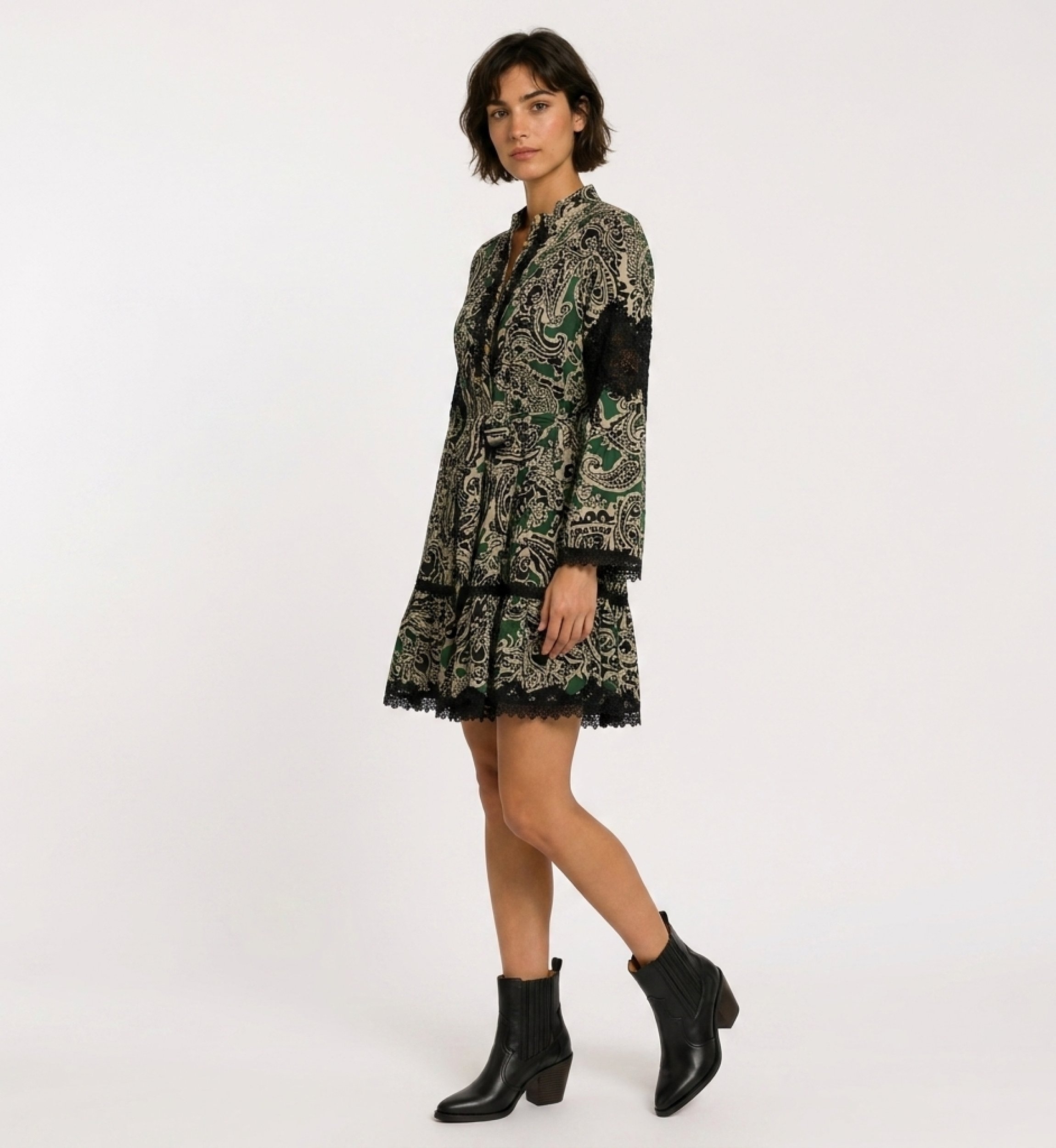 Green, black & beige paisley print mini dress, long sleeve, collared, tiered skirt, tie-waist, black lace trim, 3/4 side view.