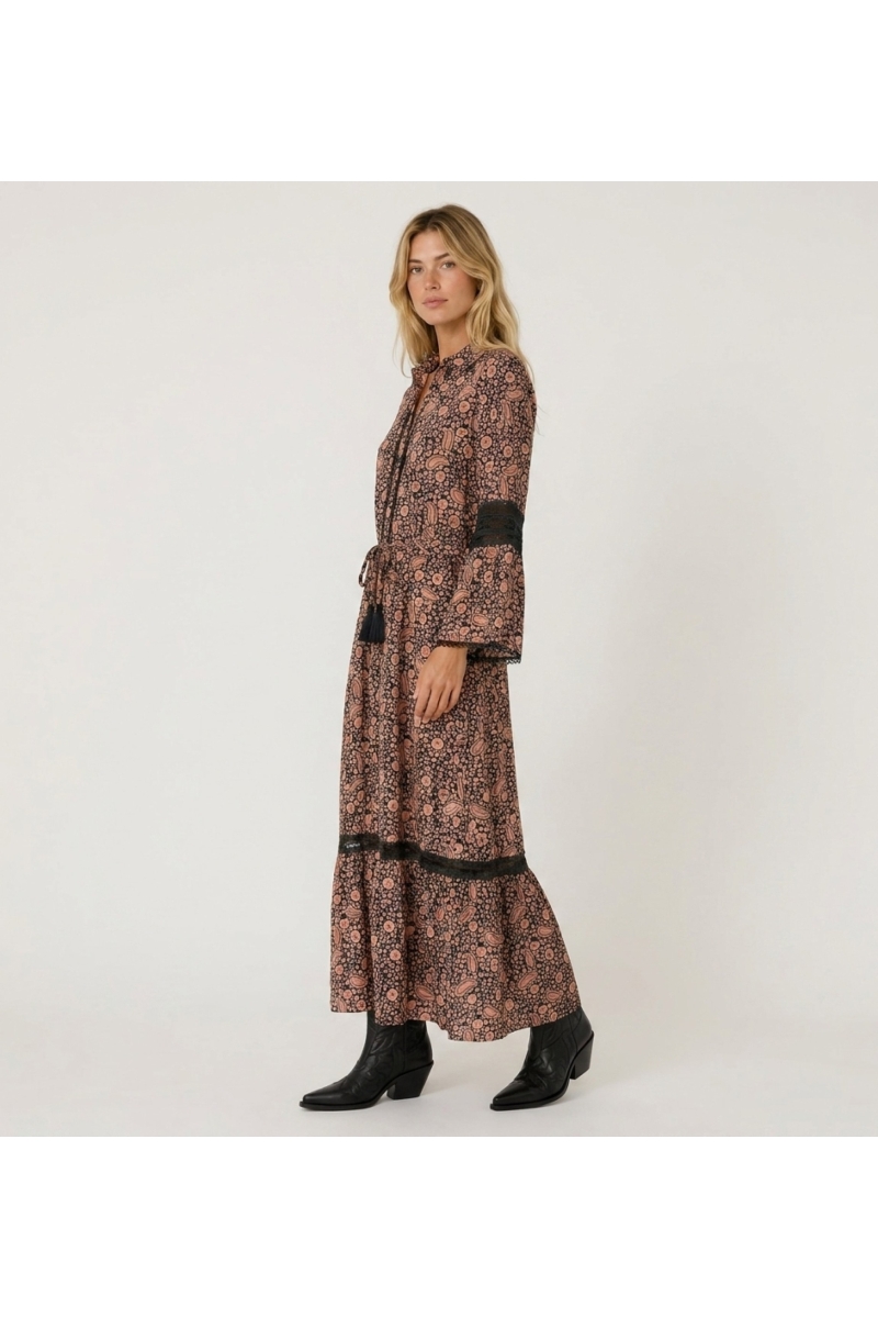 Three-quarter view of a black and peach paisley print long-sleeve maxi dress with collared neckline, smocked waist, and lace tri
