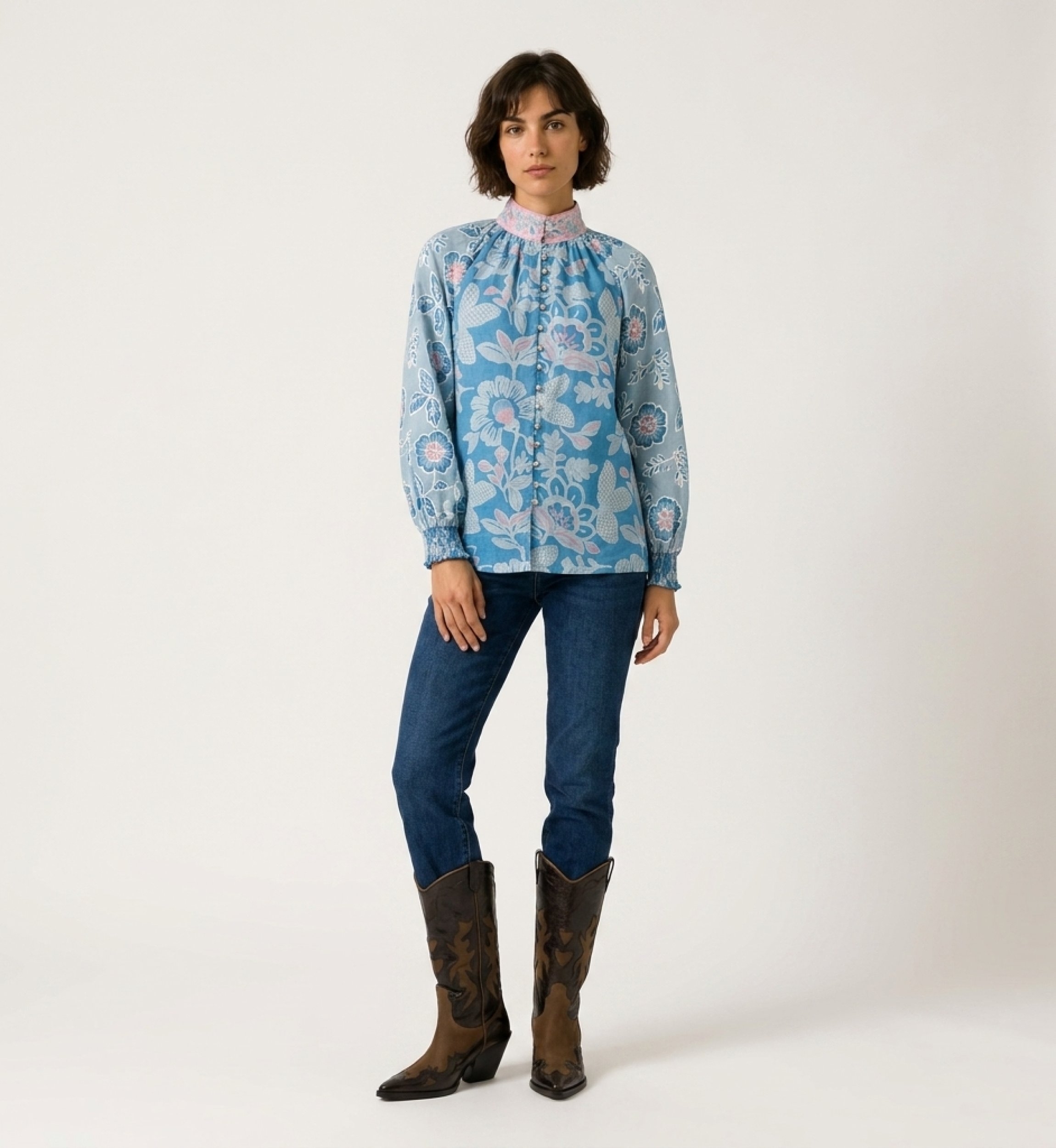 Vista frontal de blusa azul de manga larga con estampado floral rosa y blanco, cuello alto y corte holgado.