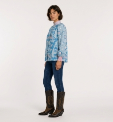 Blusa azul manga larga con estampado floral rosa y blanco, cuello alto, corte holgado, tela tipo algodón, vista de 3/4.