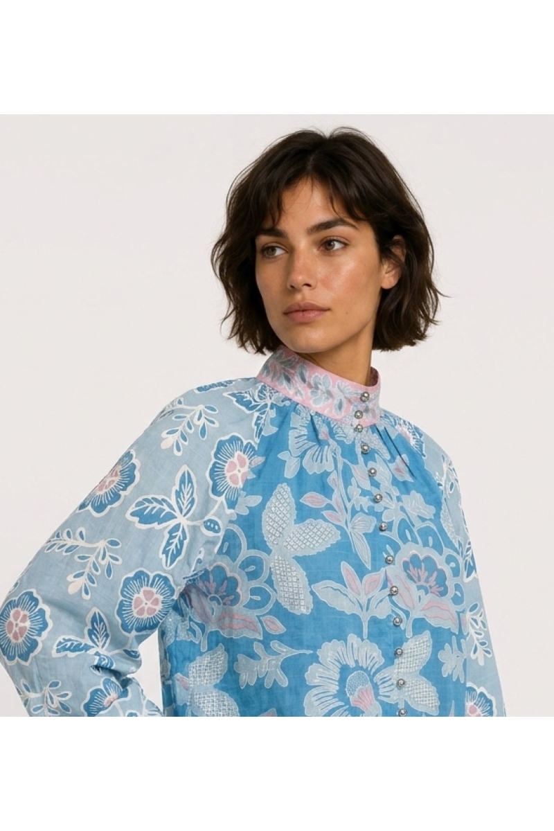 Blusa azul de manga comprida com estampa floral rosa e branca, gola alta e caimento solto em tecido de algodão, vista lateral.