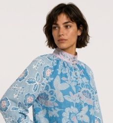 Blusa azul de manga comprida com estampa floral rosa e branca, gola alta e caimento solto em tecido de algodão, vista lateral.