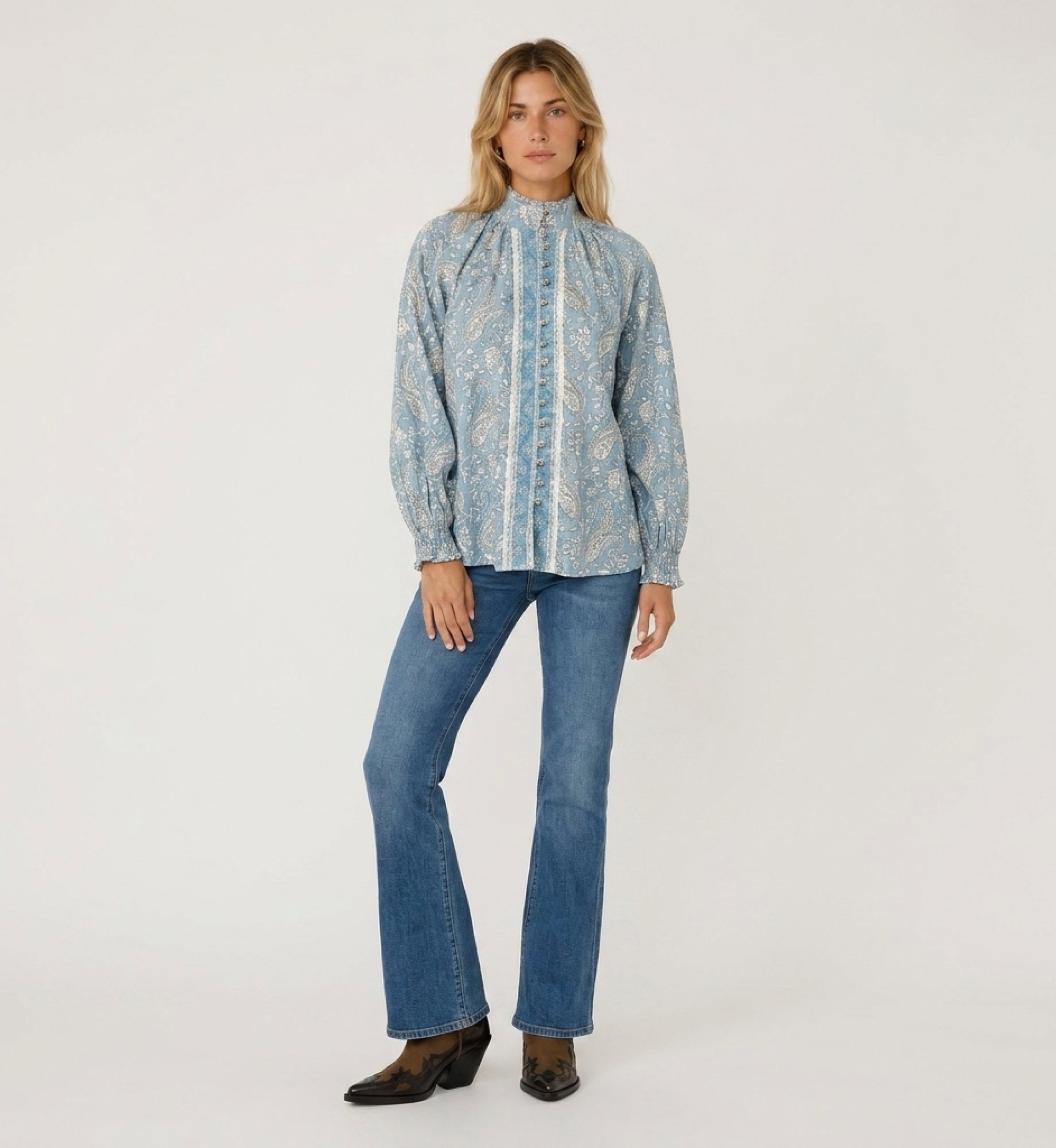 Blusa azul claro de manga longa com estampa paisley branca, gola alta, abotoada na frente e punhos com babados.