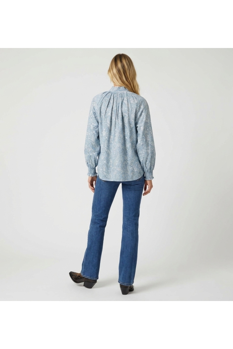 Light blue long-sleeve blouse with white paisley pattern, high collar, ruffled cuffs, back view. Elegant button-down shirt.