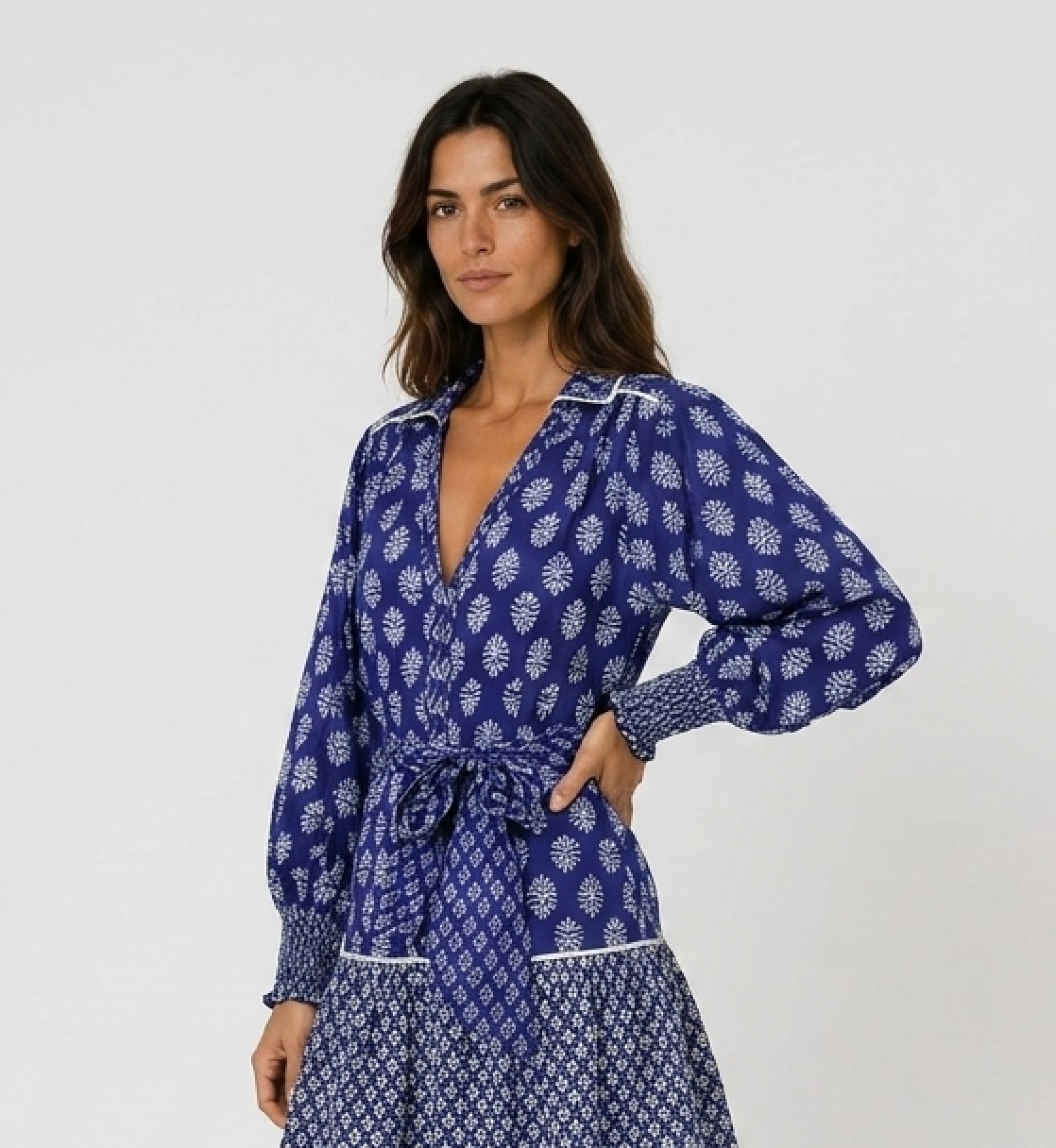 Vista três quartos de blusa azul com estampa floral, decote V, manga longa e punhos smock.