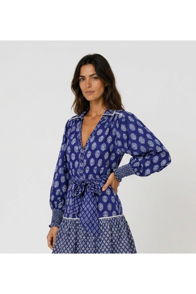 Vista tres cuartos de blusa azul con estampado floral, cuello en V, manga larga y puños smock.