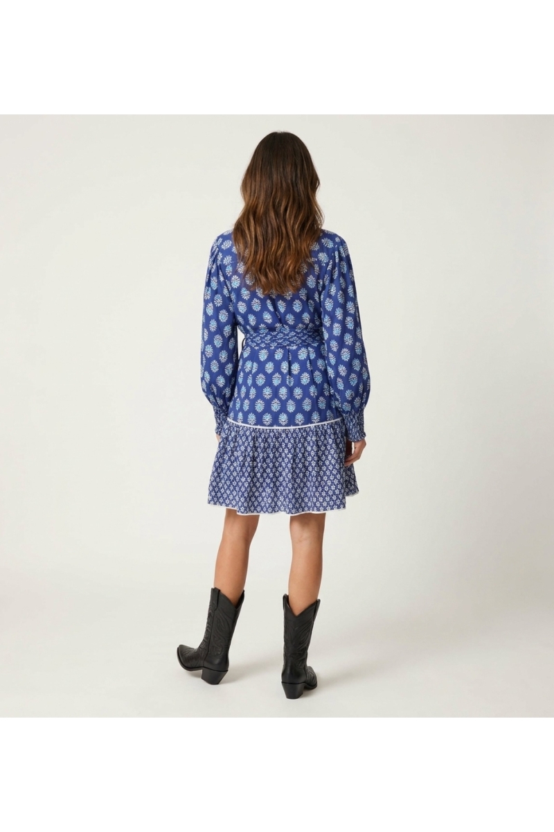 Vista trasera de blusa azul ligera de manga larga con estampado floral blanco/azul claro, cuello V y puños fruncidos.