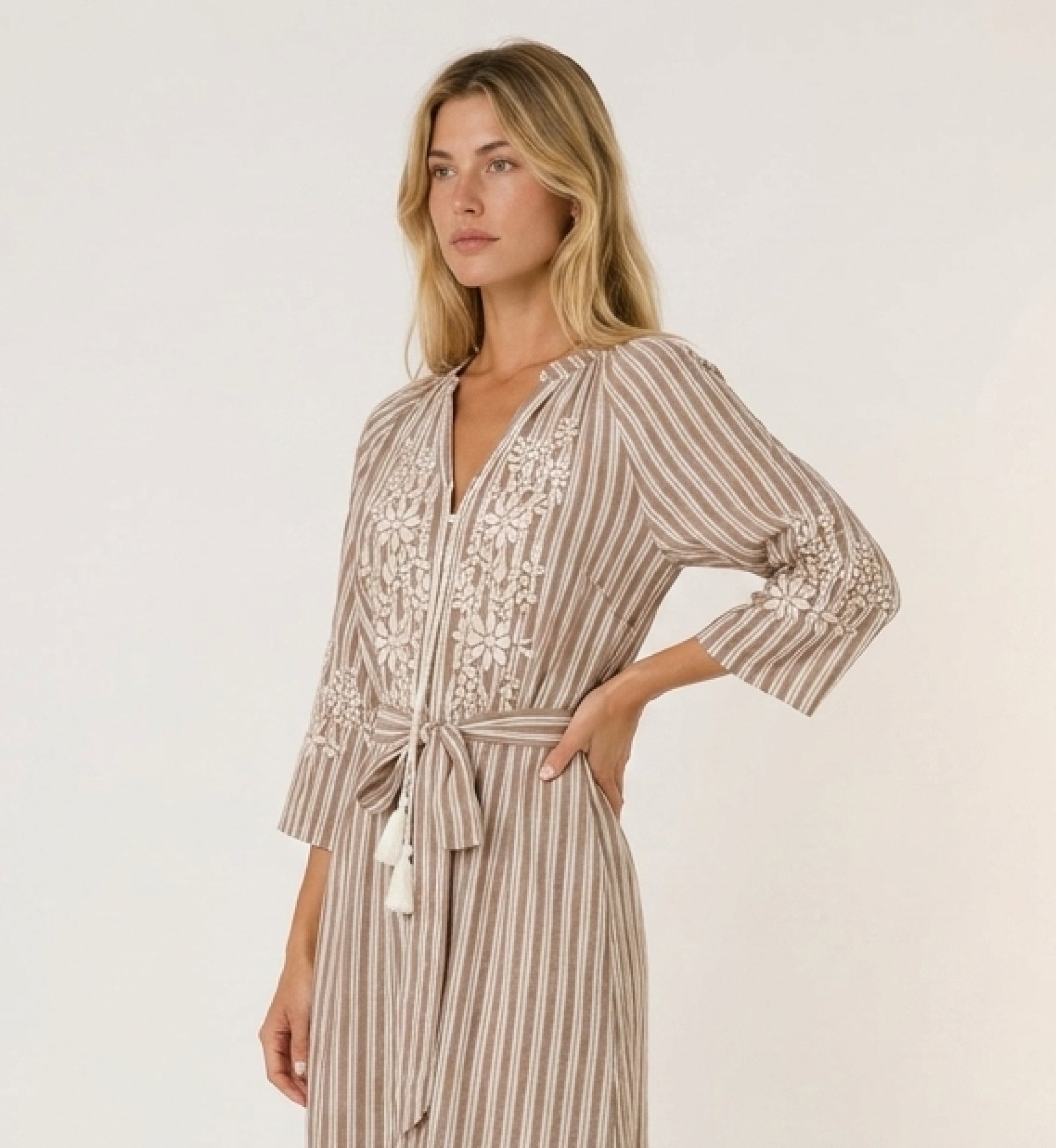 Vestido midi a rayas marrones y blancas con falda escalonada, bordado floral blanco y cintura con lazo y borlas.