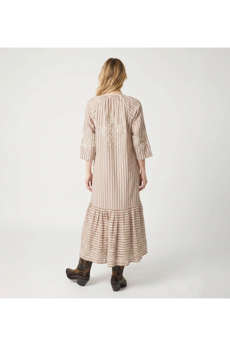 Back view of a brown and white striped midi dress with a tiered skirt, white floral embroidery, tie waist, and tassels.