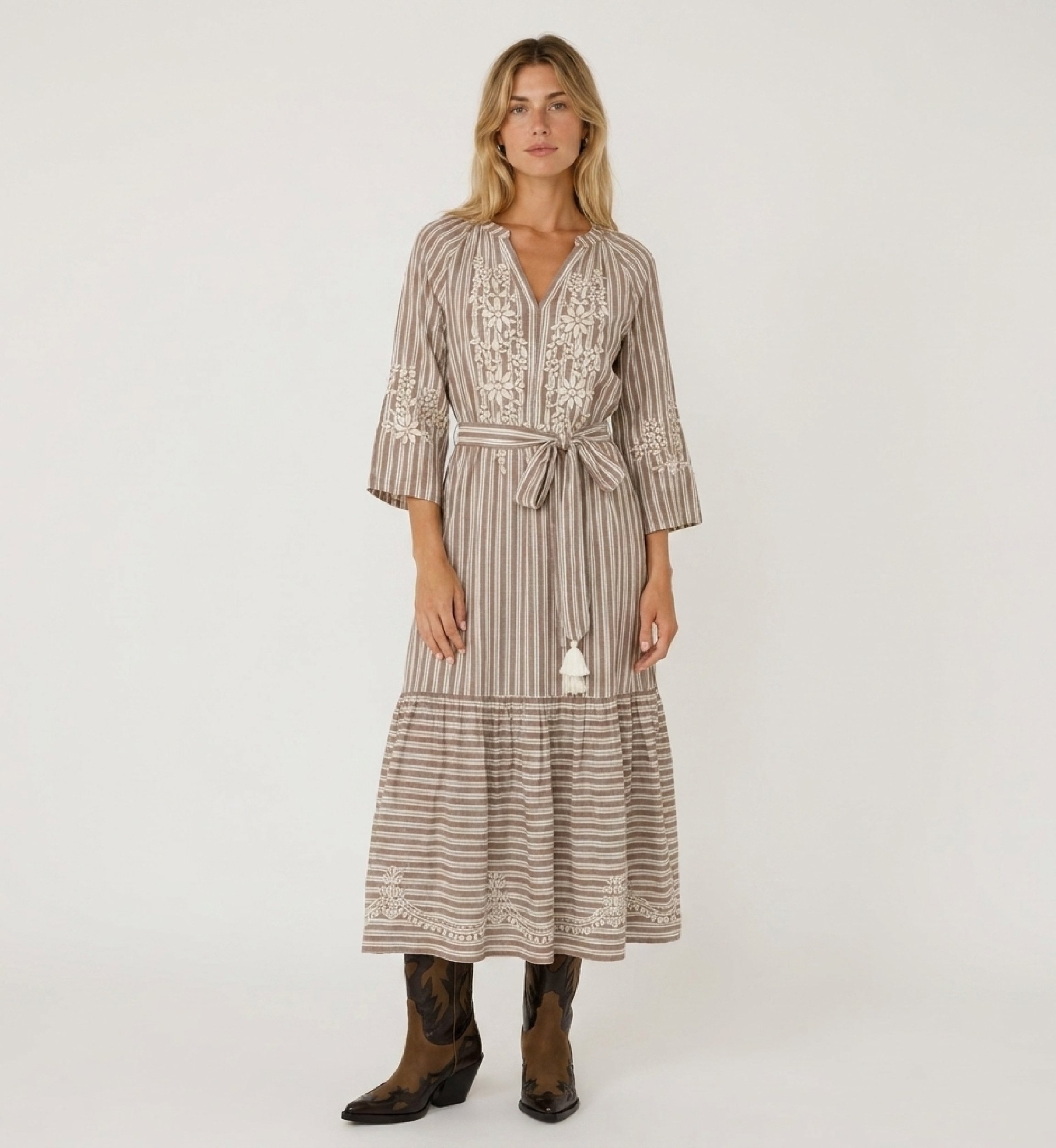 Front view of a brown and white striped midi dress with tiered skirt, white floral embroidery, and tie waist with tassels.