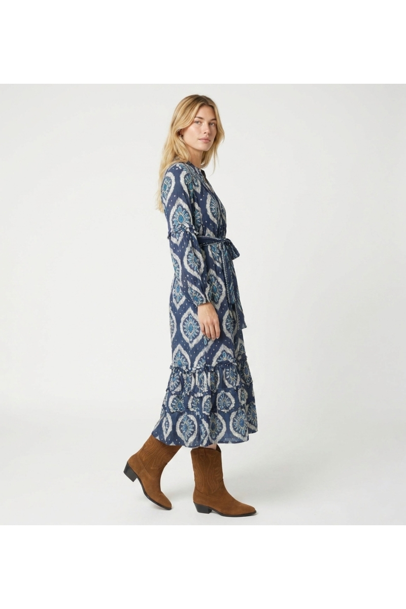 Vestido midi azul y blanco estampado ikat, mangas largas abullonadas, falda escalonada, cinturón con lazo, vista tres cuartos.