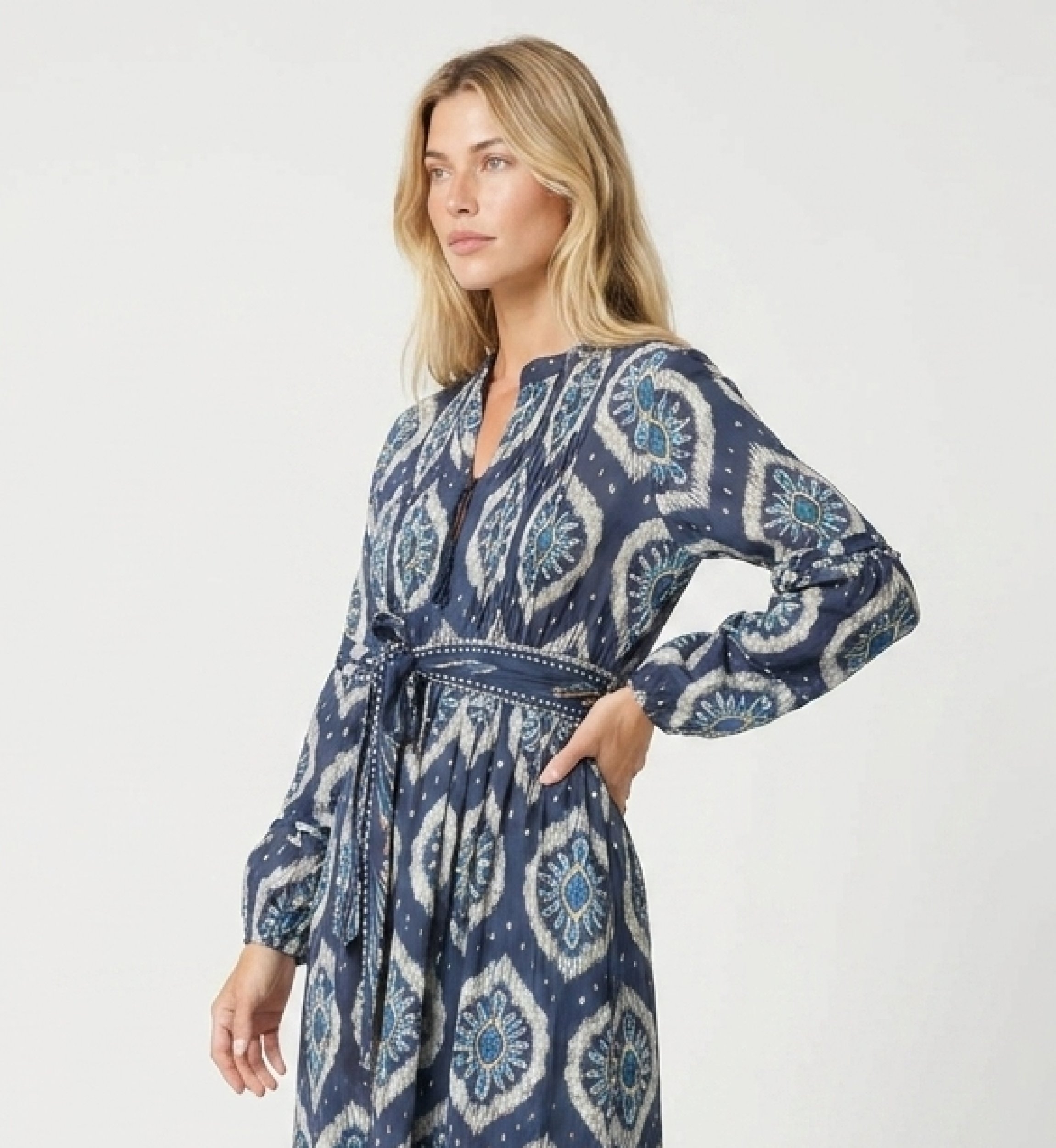 Vista três-quartos de vestido midi ikat azul e branco, manga bufante, saia em camadas e cinto com laço.