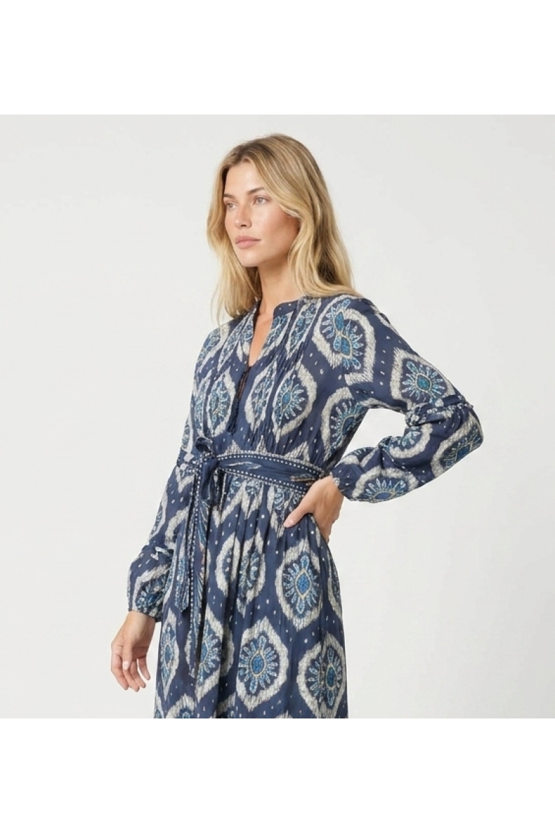 Three-quarter view of a blue and white ikat midi dress with long puff sleeves, tiered skirt, and tie belt.