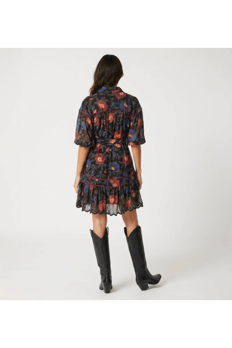 Minivestido preto gola, estampa floral vermelha e azul, mangas balão 3/4, cintura amarrada, barra em camadas, vista costas.