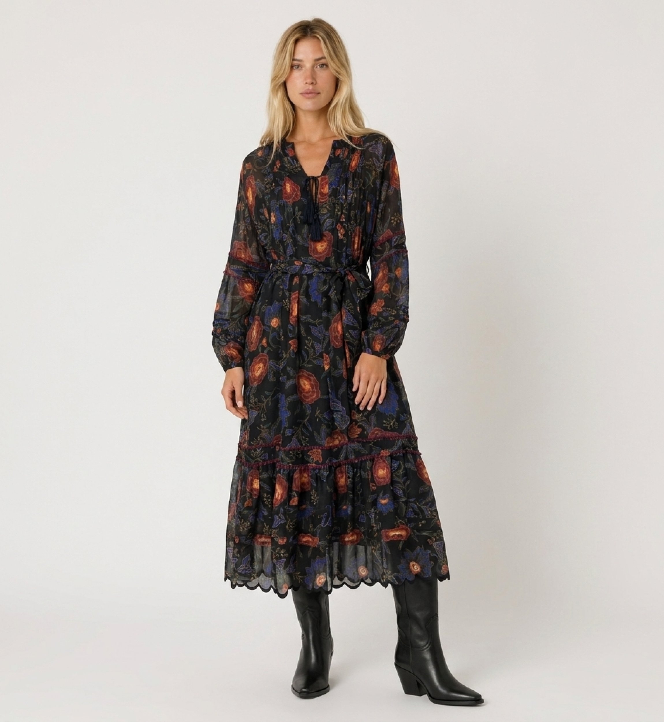 Vestido midi negro de manga larga con estampado floral rojo y azul, falda escalonada, cintura anudada, tela ligera.