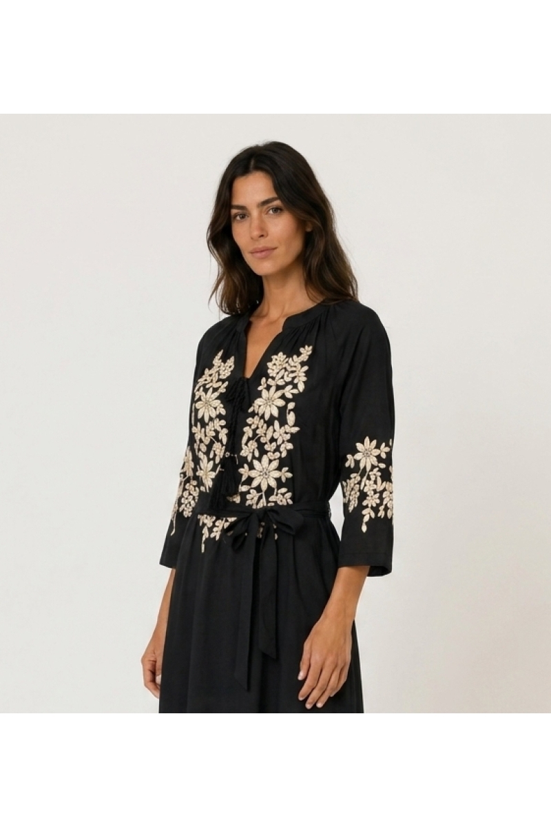 Vestido midi campesino negro, corte holgado, bordados florales dorados en corpiño, mangas y bajo, cintura anudada, vista 3/4.