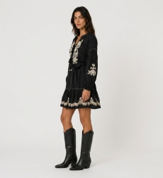 Mini vestido negro holgado, mangas globo largas, falda escalonada, bordado floral blanco, cintura anudada. Vista 3/4.