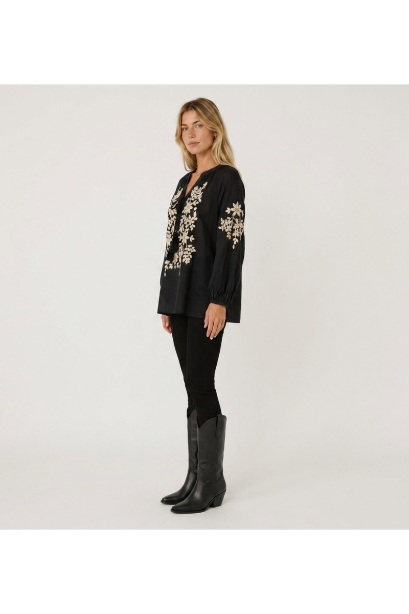 Black long-sleeve peasant blouse with v-neck, tie, and cream floral embroidery. Linen-look fabric, three-quarter view.