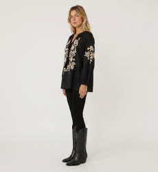 Blusa campesina negra de manga larga con cuello en V y lazo. Bordado floral crema, tejido tipo lino, vista 3/4.