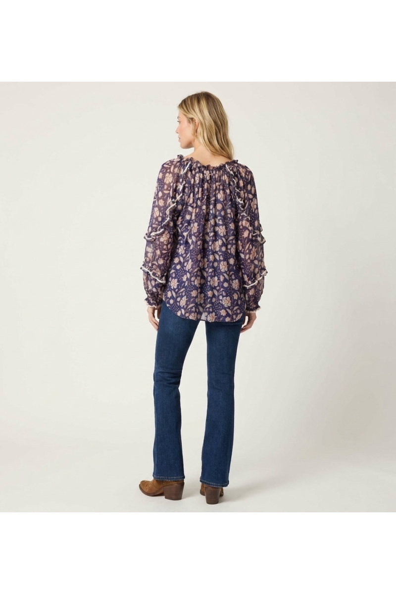 Back view of a sheer navy blue floral blouse with white and peach pattern, ruffled long sleeves, and loose fit.
