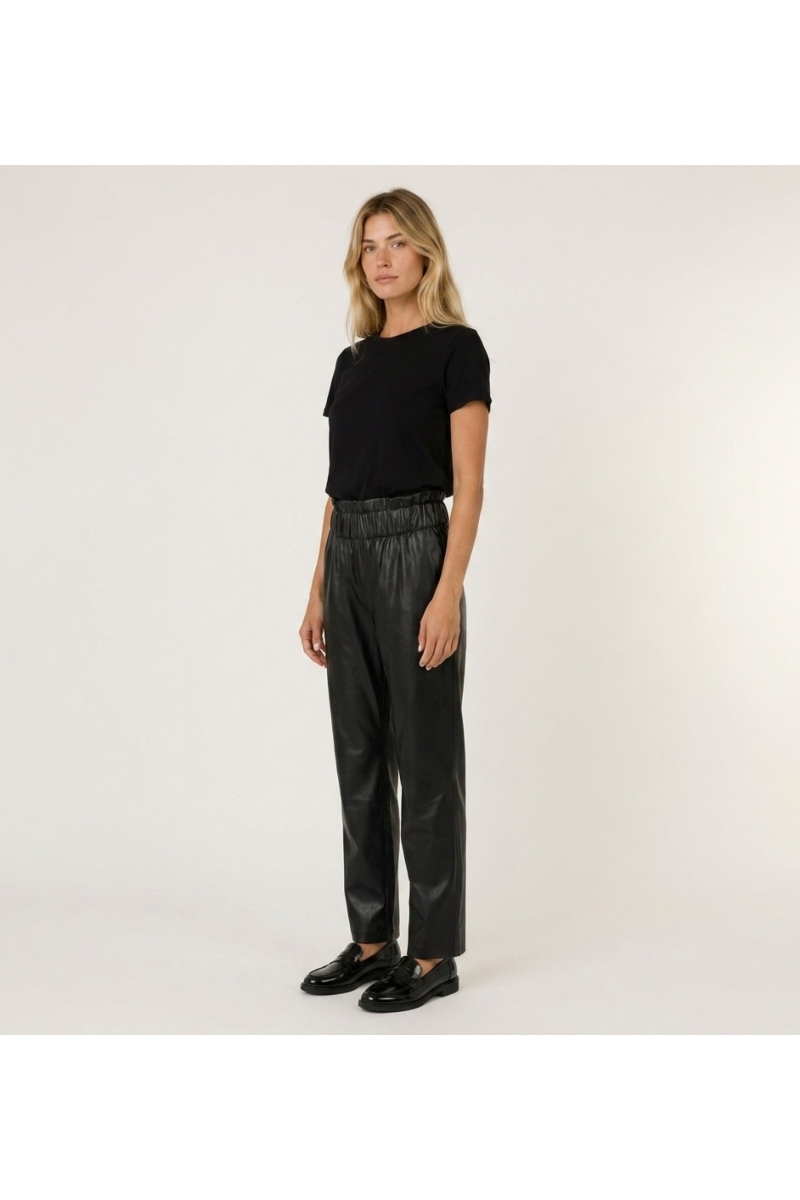 Calça de couro preta feminina, corte ajustado, vista lateral de três quartos, realçando o caimento e a textura.