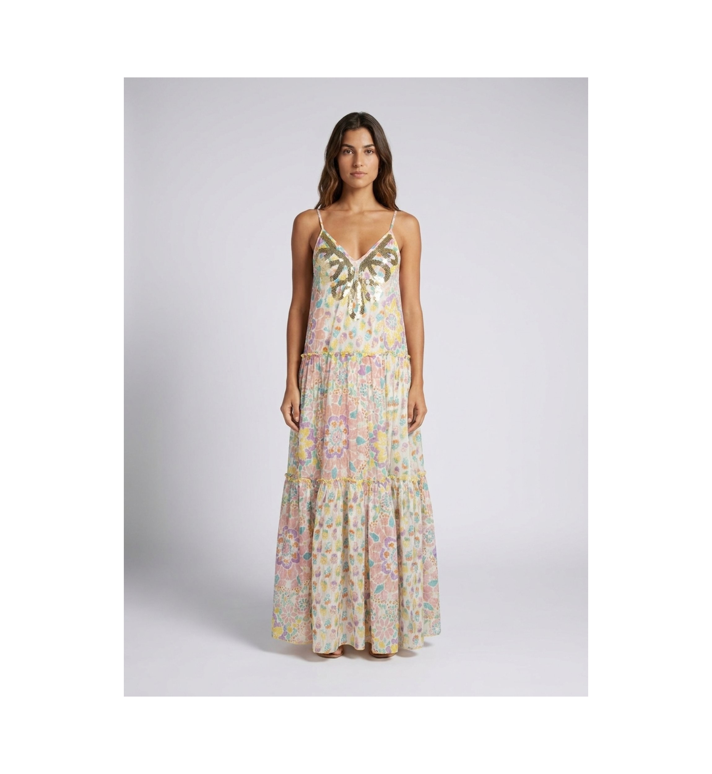 Front view: White tiered maxi dress with thin straps, V-neck, and vibrant multicolored floral print. Sequin embellished neckline