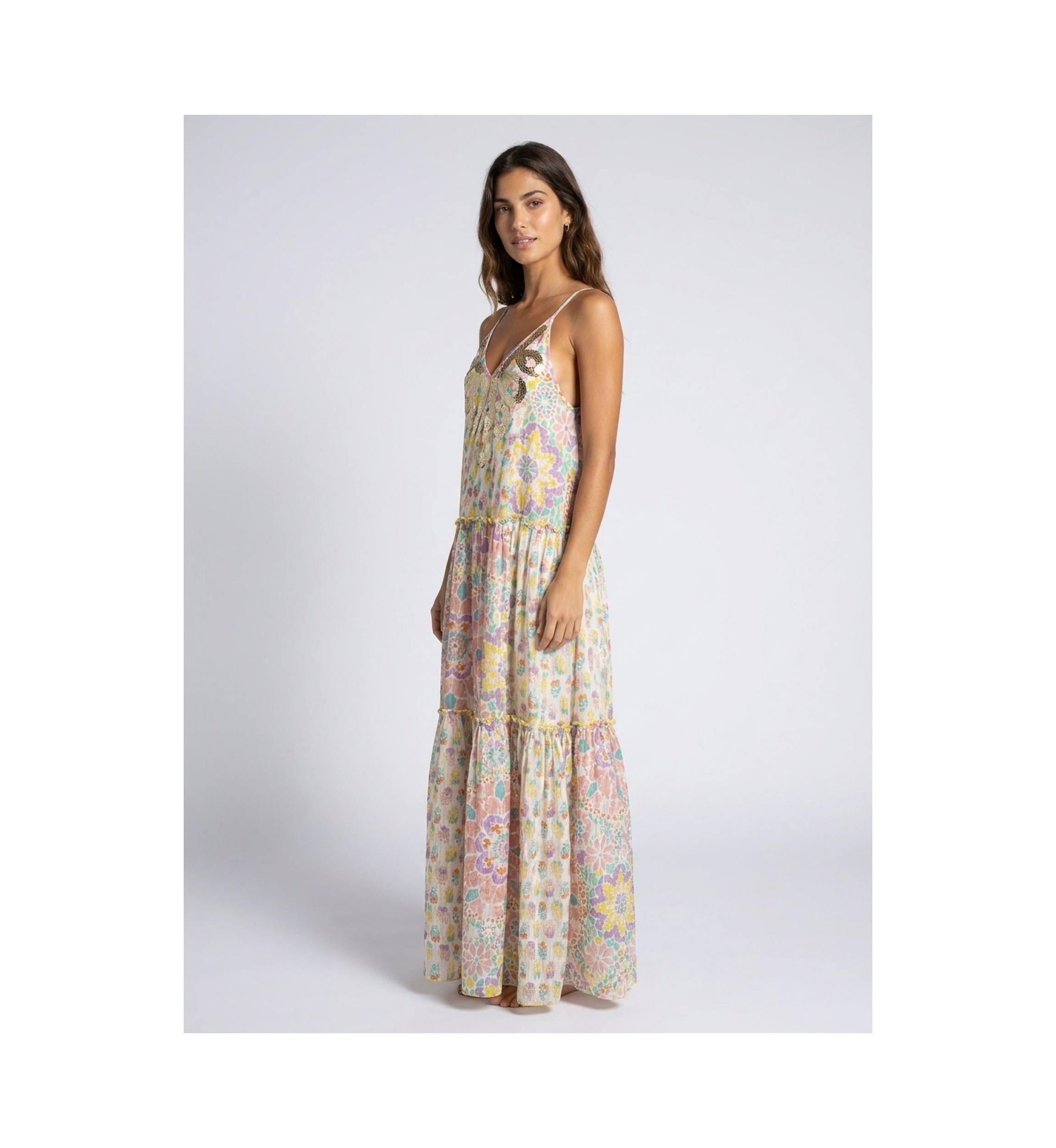 White long tiered maxi dress, thin straps, V-neck with gold/silver sequins, vibrant floral pattern, model side view.