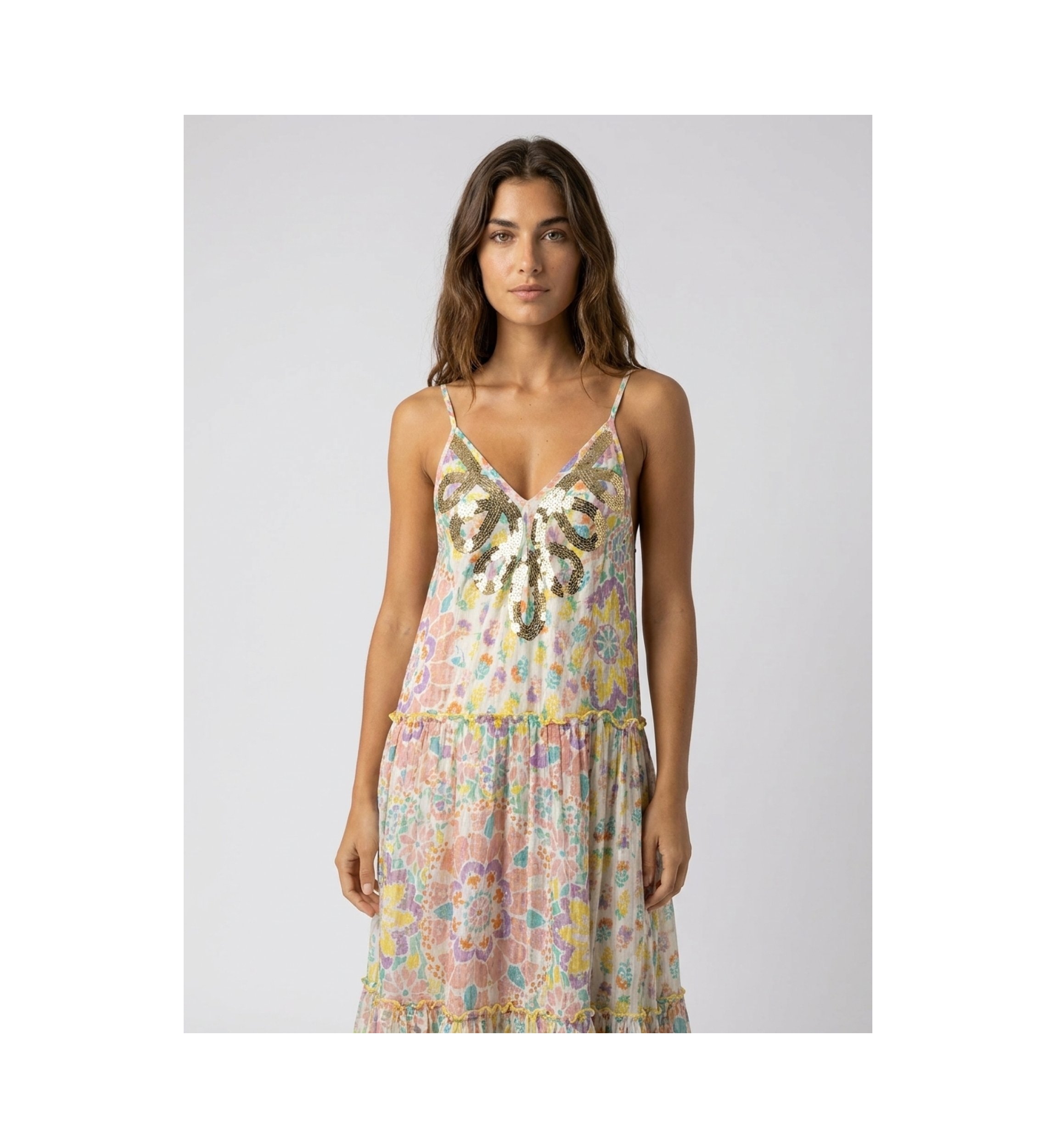 White tiered maxi dress with thin straps, sequined V-neckline, and vibrant multicolored floral print.