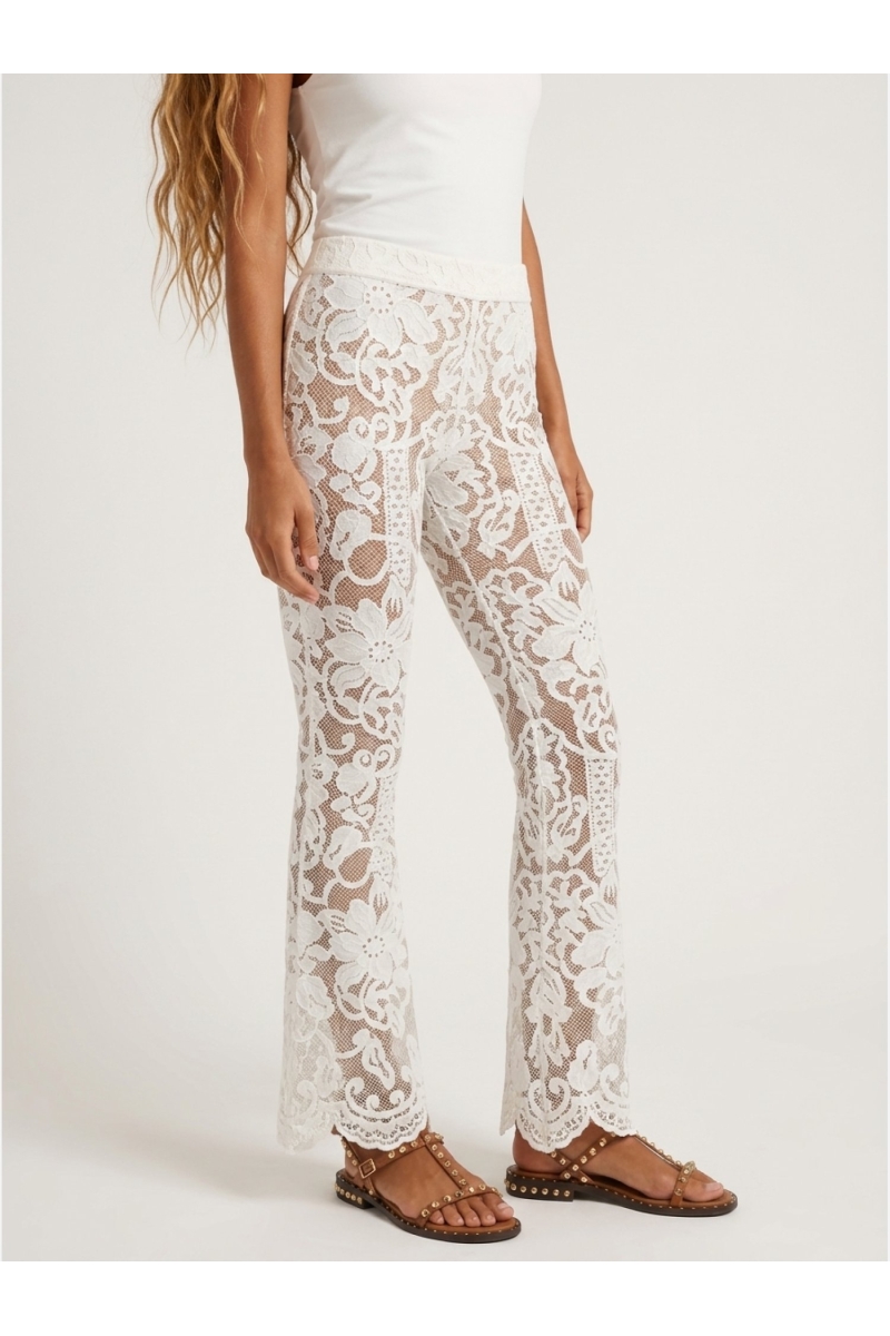 Close-up of white floral lace flared trousers with nude lining and scalloped hem. Elegant women's fashion.