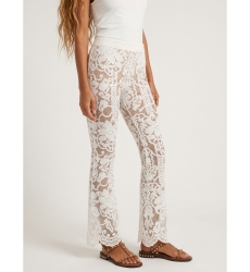 Primer plano de pantalón acampanado de encaje blanco floral, forro nude y bajo festoneado. Moda femenina elegante.