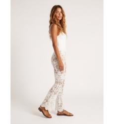 White lace flared trousers with floral pattern, nude lining, and scalloped hem, shown on model side view.