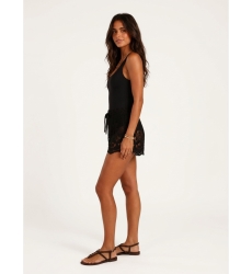 Short de crochê preto folgado, com padrões florais e de folhas, cintura com cordão, em modelo visto de lado.