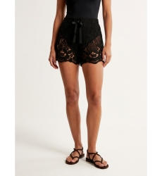 Primer plano de shorts negros de crochet, corte holgado, con intrincados motivos florales y de hojas, y cintura con cordón.